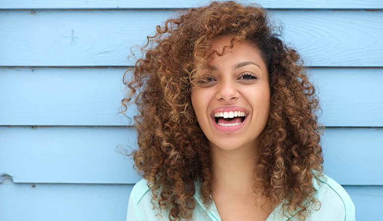 girl with curly hair shows off her dental veneers