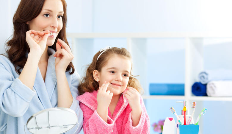 mom showing daughter about preventive dentistry and how to floss