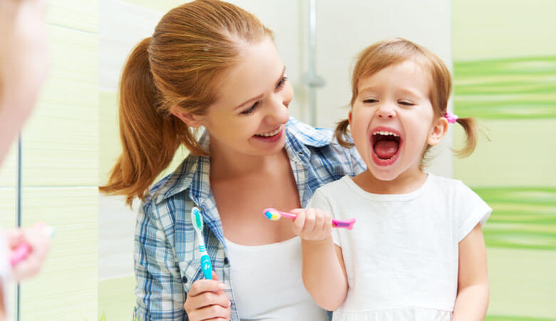 parent teaching kid to brush teeth