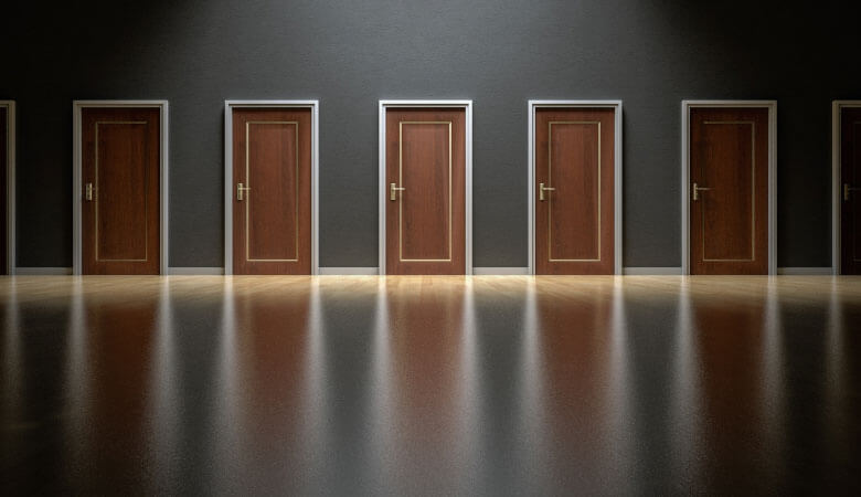 a grey room with wood floors with a row of brown closed doors