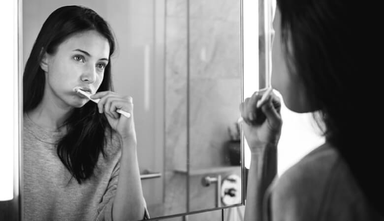 girl looking in the mirror brushing her teeth