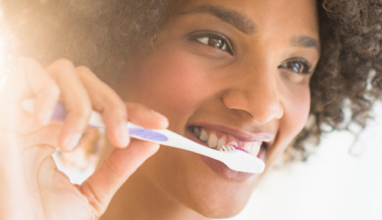 young woman  brushing her teeth to prevent yellow teeth