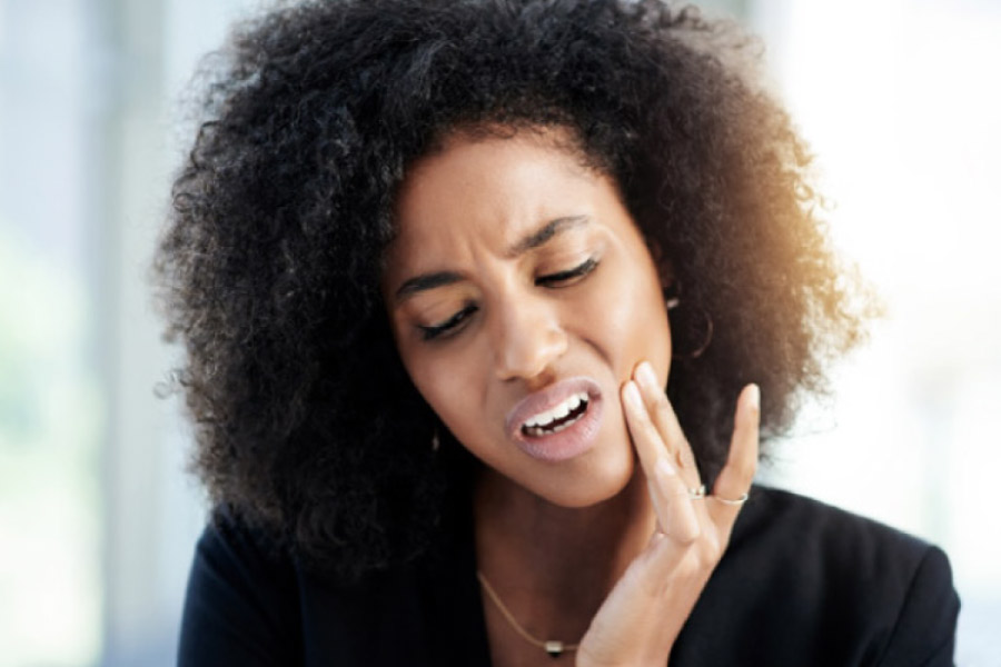 dark haired woman holds her jaw in pain with an infected tooth