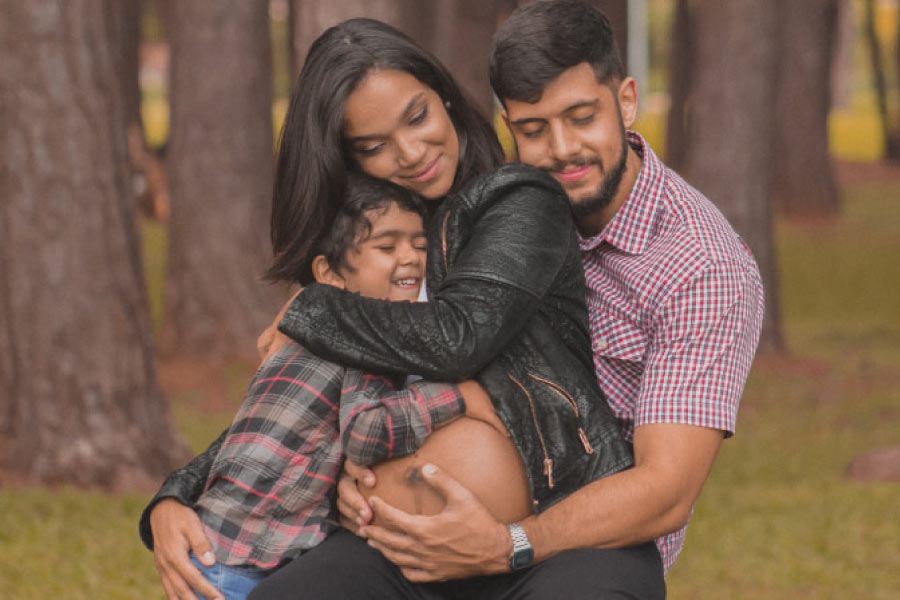pregnant woman hugging with her young son and husband