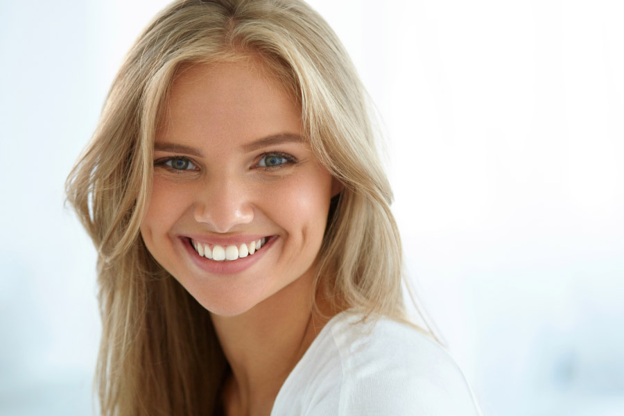 young woman smiles showing off her professionally whitened teeth