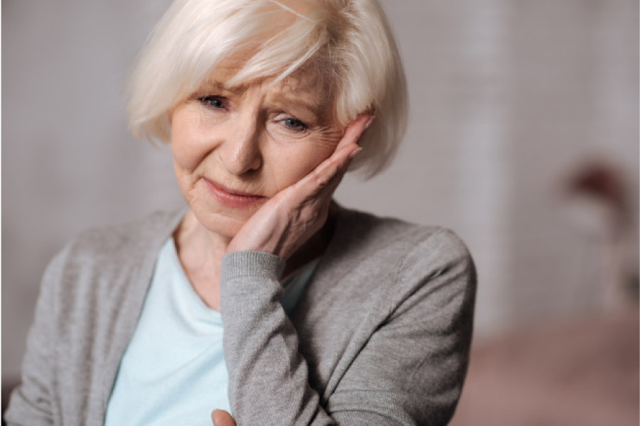 senior woman holds her jaw with sensitive tooth pain