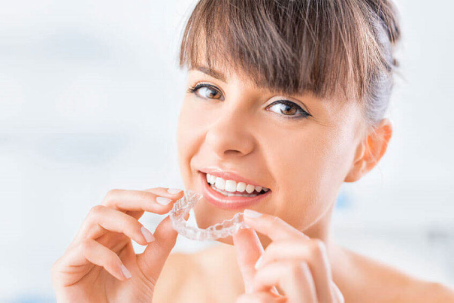 young woman inserts a clear aligner to straighten her teeth