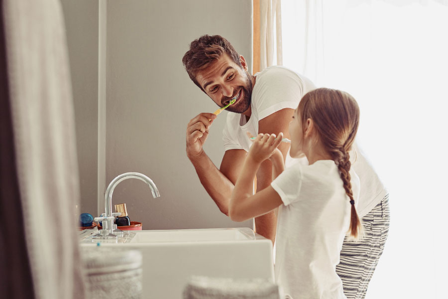 father brushing his teeth with his young daughter